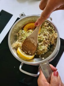 Holderblüten und Orangenscheiben werden mit Kochlöffel ausgedrückt