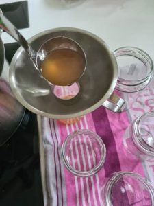 Flüssigkeit wird durch Trichter in Marmeladegläser gefüllt
