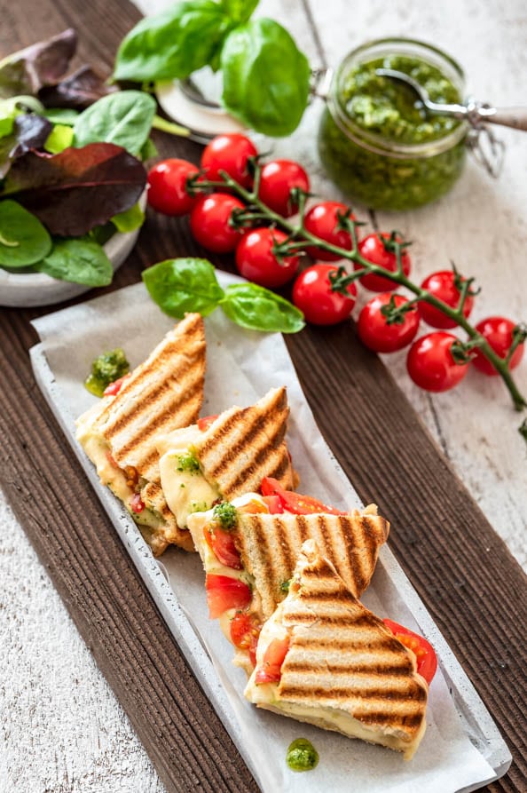 Toast mit Tomaten, Mozzarella und Basilikumpesto ist in kleinen Dreiecken angerichtet