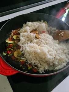 Reis wird in Pfanne mit Gemüse gegeben