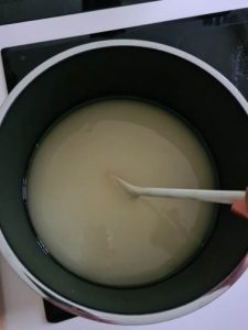 Holundersaft wird mit Zucker in Kochtopf aufgekocht