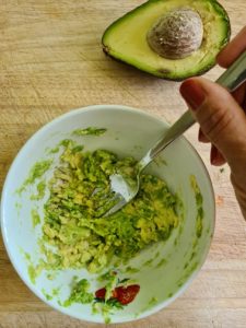 Avocado wird in Schale mit Gabel zerdrückt